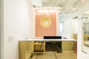 핑크 포인트월과 골드 조명의 필라테스 리셉션